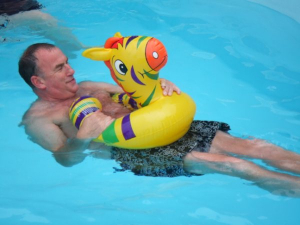 Photo of Andrew Levick reclining in a swimming pool with an inflatable friend